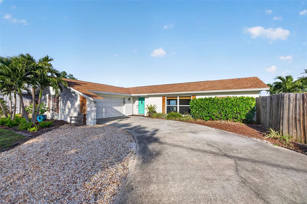 A single-story house with a white stone facade, a teal front door, and a driveway — 4200 BEACH DRIVE SE, ST PETERSBURG, FL