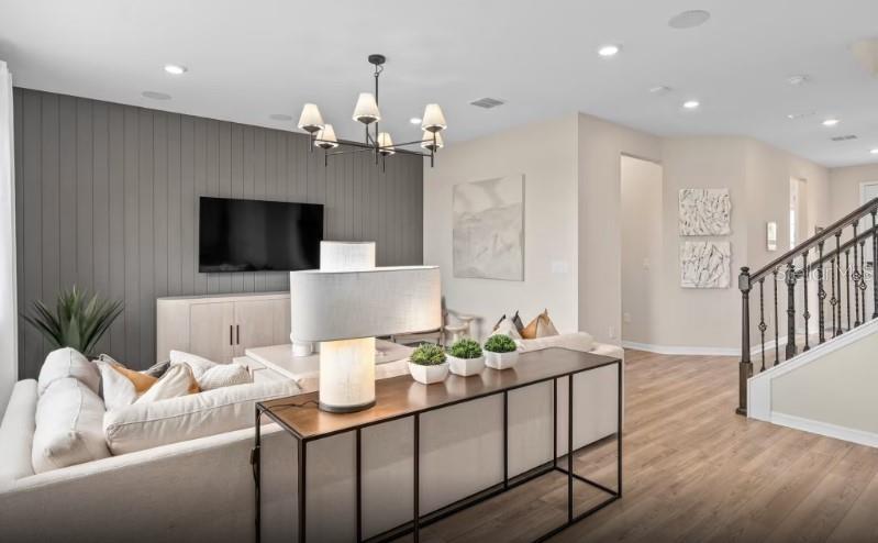 A living room features a gray shiplap accent wall, a chandelier, and a sofa console — 7456 SUMMER COURT, SARASOTA, FL