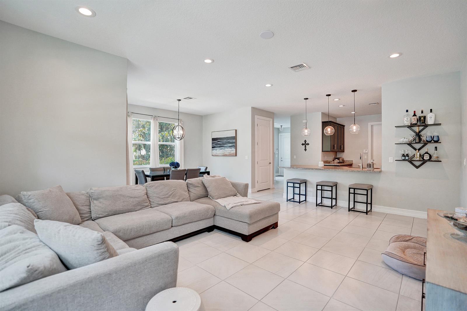 An open-concept living room features a large sectional sofa, dining area, and kitchen island — 99 Palm Lane, Royal Palm Beach FL 33411, ROYAL PALM BEACH, FL