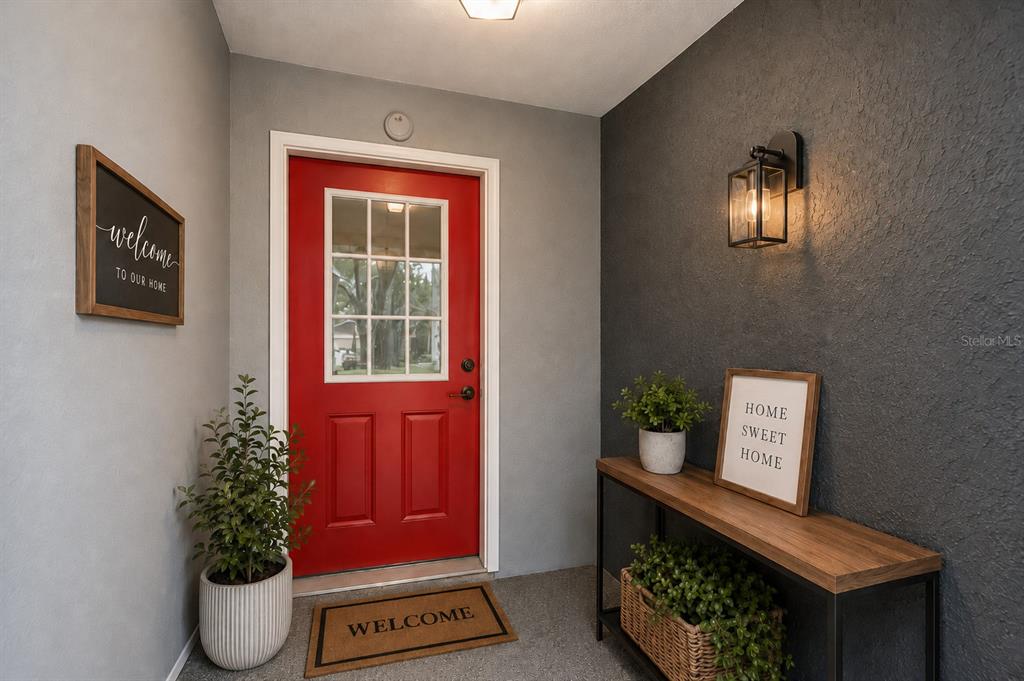 A red front door stands between a gray wall and a dark accent wall — 7969 SOMERSET DRIVE, LARGO, FL