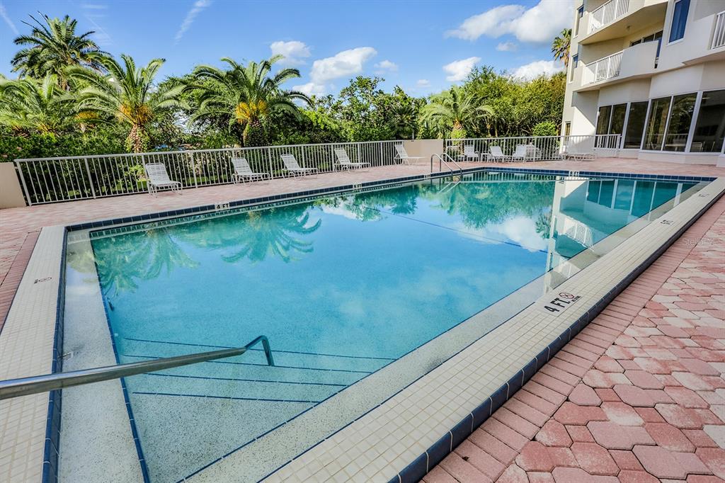 A rectangular swimming pool with a metal handrail is surrounded by a brick paver deck — 3 OCEANS WEST BOULEVARD UNIT 7C1, DAYTONA BEACH, FL