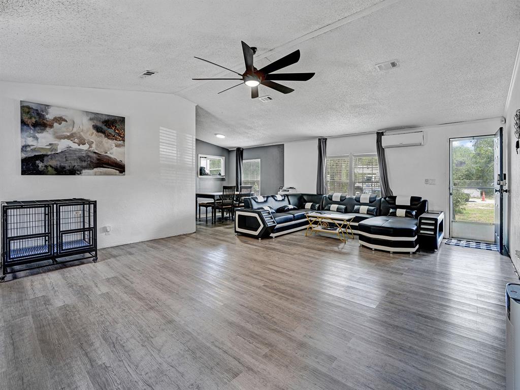 A spacious living room features light wood-look flooring, a ceiling fan, and a sectional sofa — 12845 CASA BIANCA AVENUE, NEW PORT RICHEY, FL