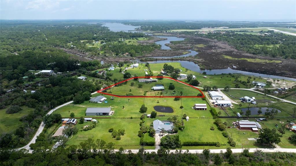 An aerial view shows a rural property with a house and outbuildings outlined in red — 1050 DILLON CIRCLE, NEW SMYRNA BEACH, FL
