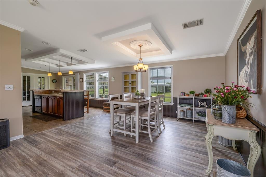 A dining area and kitchen with wood-look flooring, tray ceilings, and a wooden island — 1050 DILLON CIRCLE, NEW SMYRNA BEACH, FL