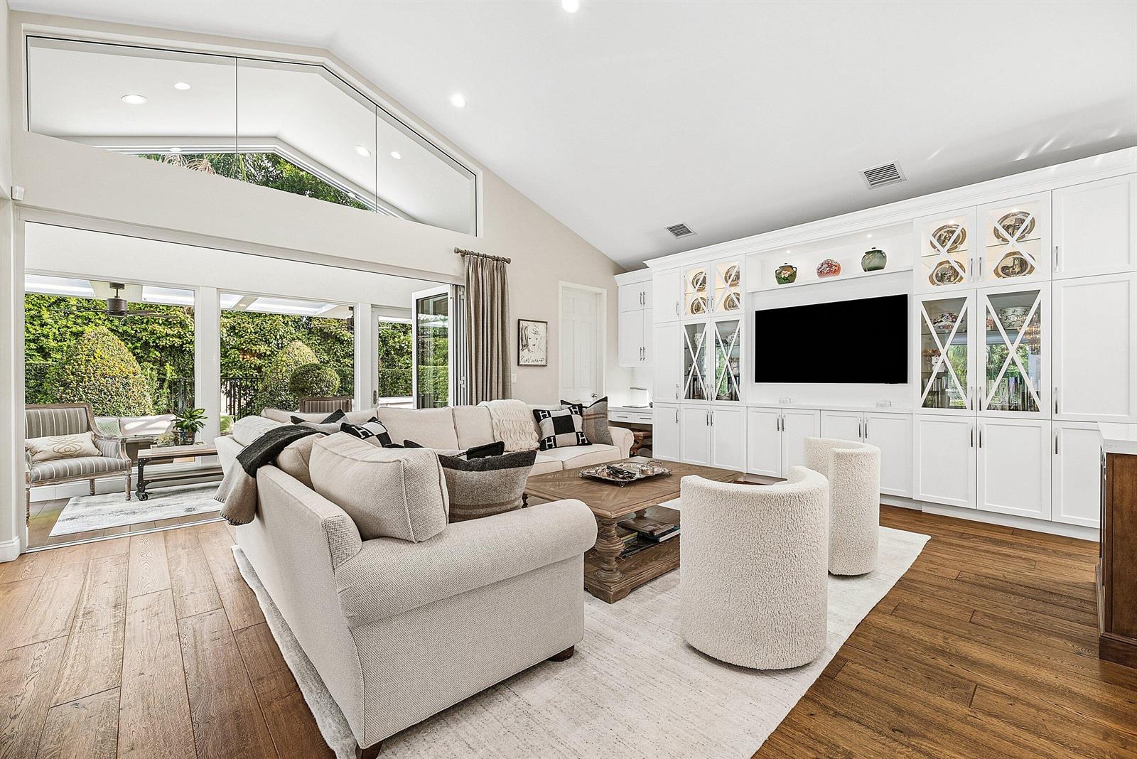 A kitchen features white cabinetry, a wood-toned island with bar stools, and a crystal chandelier — 4361 Gleneagles Drive, Boynton Beach FL 33436, BOYNTON BEACH, FL
