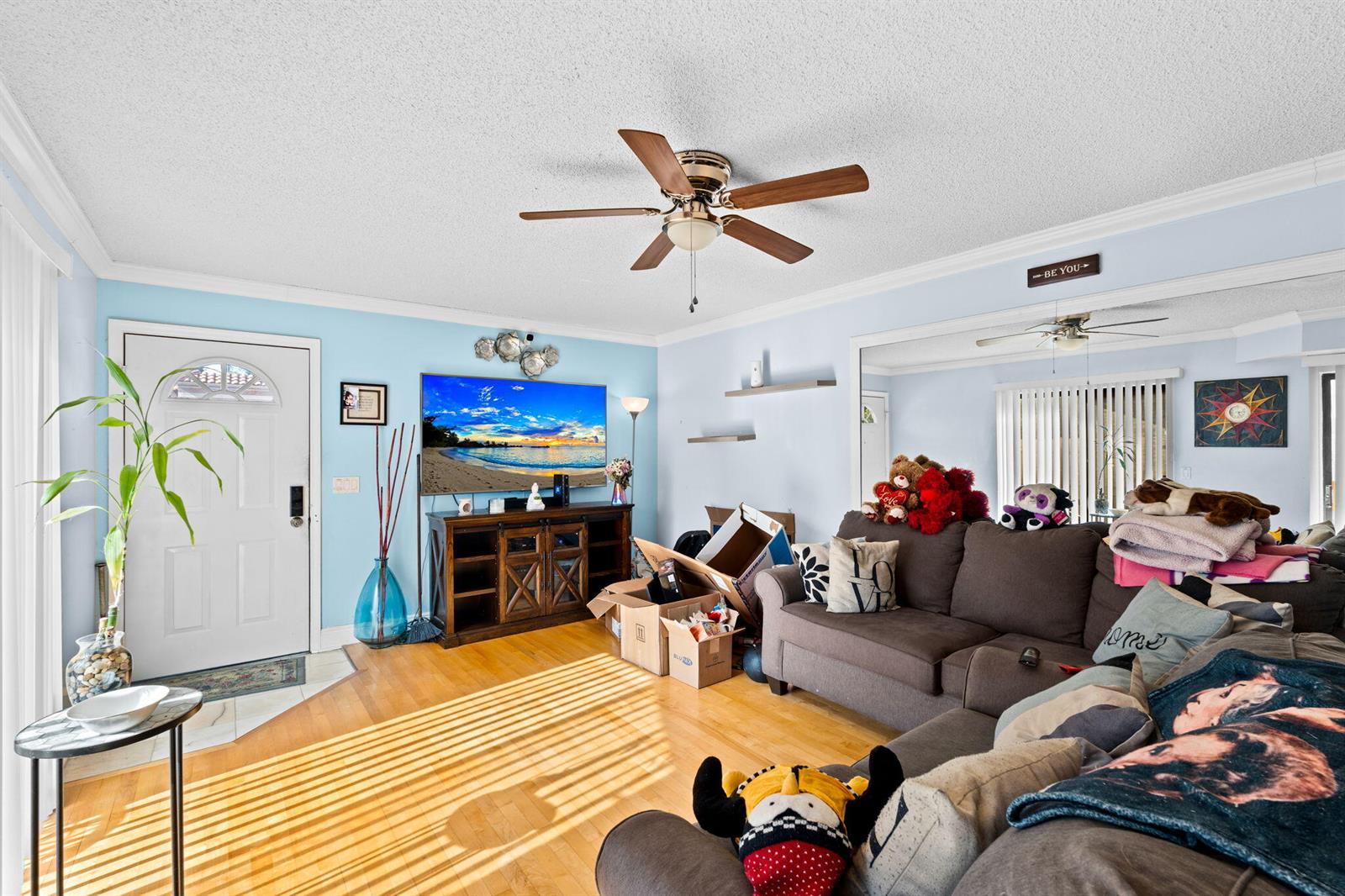 A living room features light blue walls, hardwood floors, a ceiling fan, and a sectional sofa — 6139 Seven Springs Boulevard, FL 33463, FL