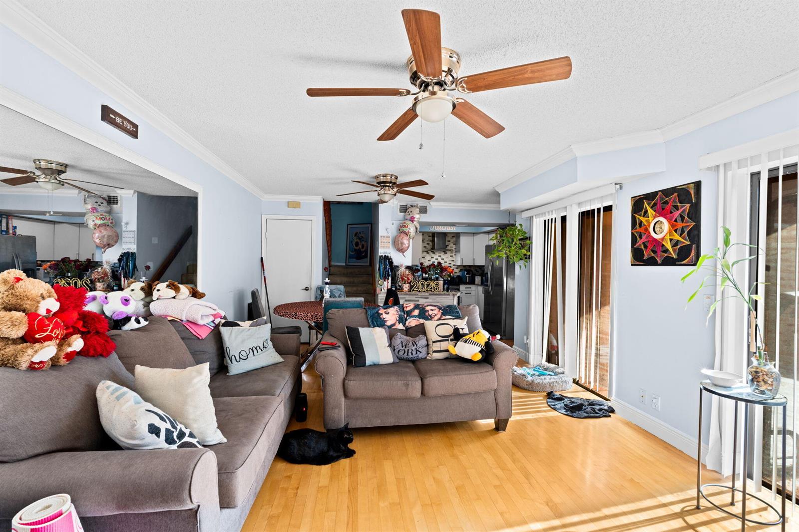 A living room with light blue walls, hardwood floors, two brown sofas, and ceiling fans — 6139 Seven Springs Boulevard, FL 33463, FL