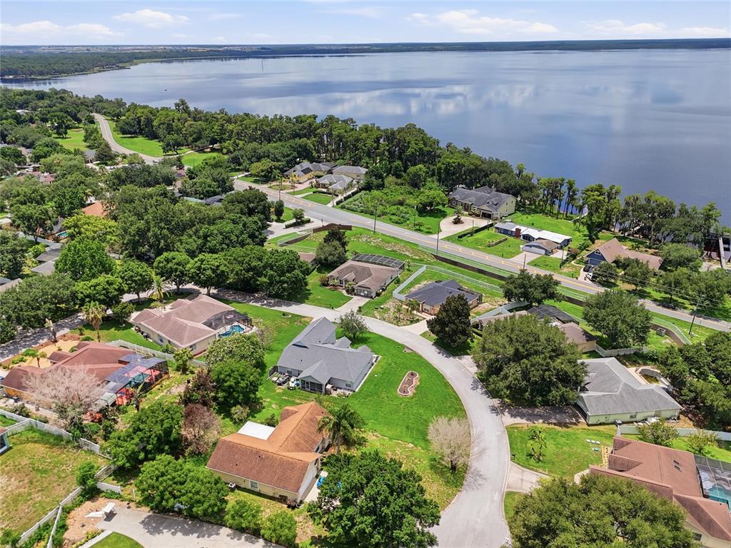An aerial view shows suburban houses with swimming pools near a large lake — 13042 SUNWOOD COURT, CLERMONT, FL
