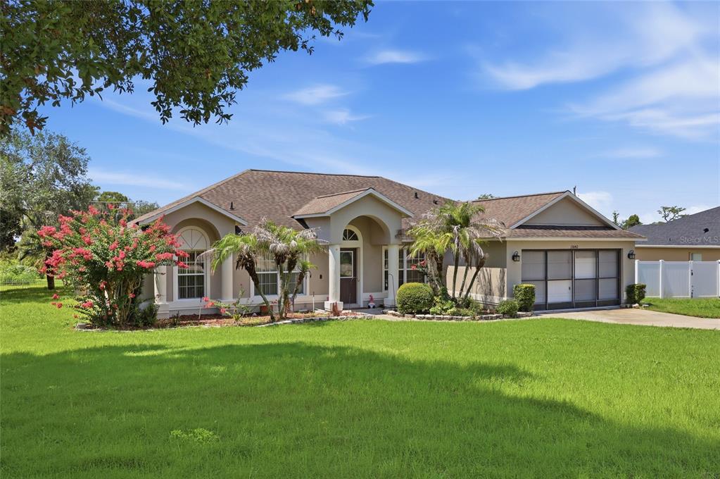 A single-story suburban house with a tan exterior, a brown roof, and a green lawn — 13042 SUNWOOD COURT, CLERMONT, FL
