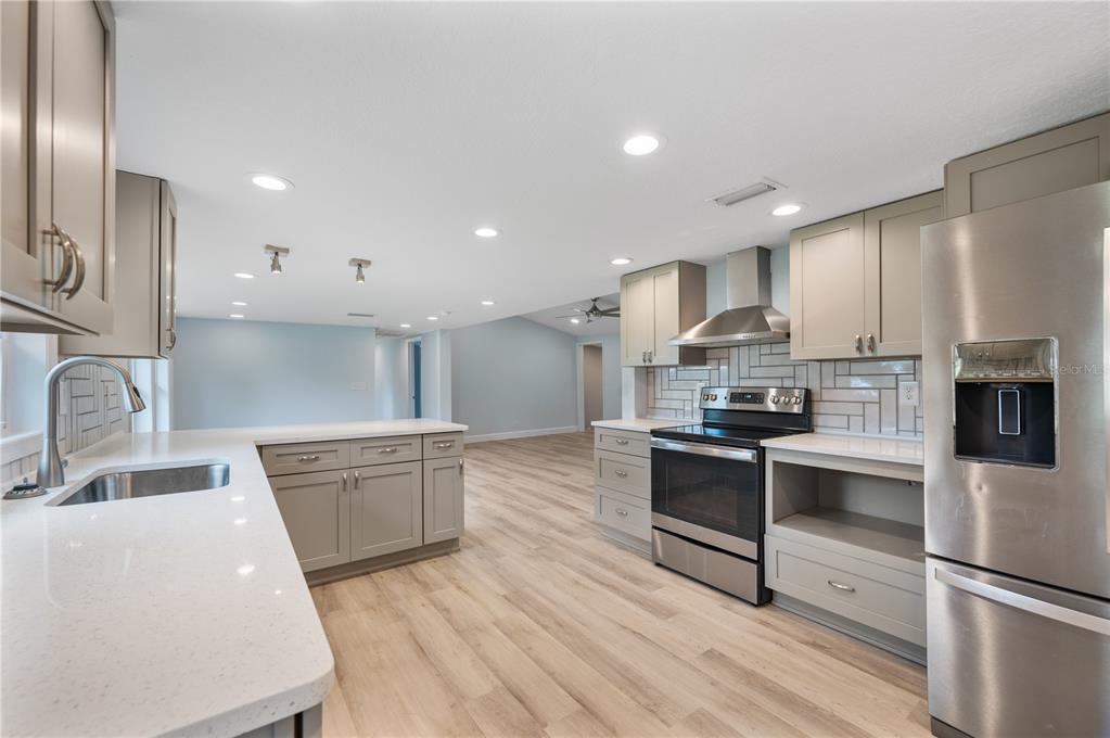 A modern kitchen features gray cabinets, stainless steel appliances, white countertops, and light wood flooring — 5418 COOPER LANE, FORT MEADE, FL