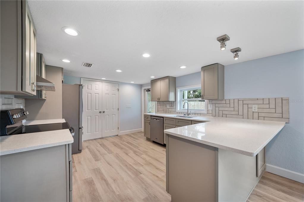 A kitchen with light gray cabinets, white countertops, a herringbone backsplash, and wood-look flooring — 5418 COOPER LANE, FORT MEADE, FL