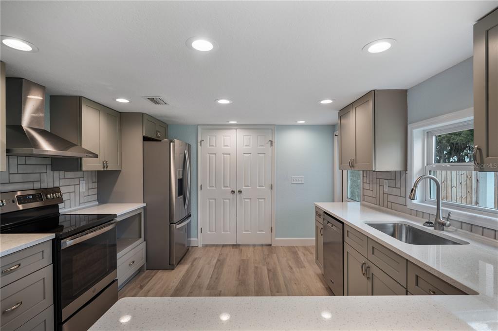 A kitchen features gray cabinets, stainless steel appliances, white countertops, and light wood-look flooring — 5418 COOPER LANE, FORT MEADE, FL