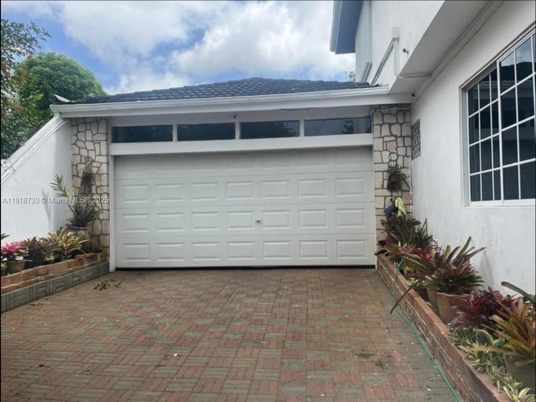 A white garage door with transom windows sits above a brick driveway with side planters — 00 WEST PALM GARDENS, BRUMALIA, MANDEVILLE,JAMAICA, NA, NA
