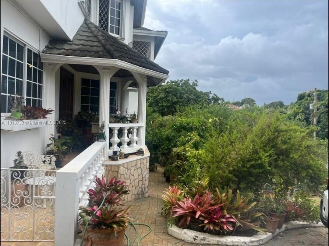 A paved walkway leads to a covered porch with white railings and stone base detailing — 00 WEST PALM GARDENS, BRUMALIA, MANDEVILLE,JAMAICA, NA, NA