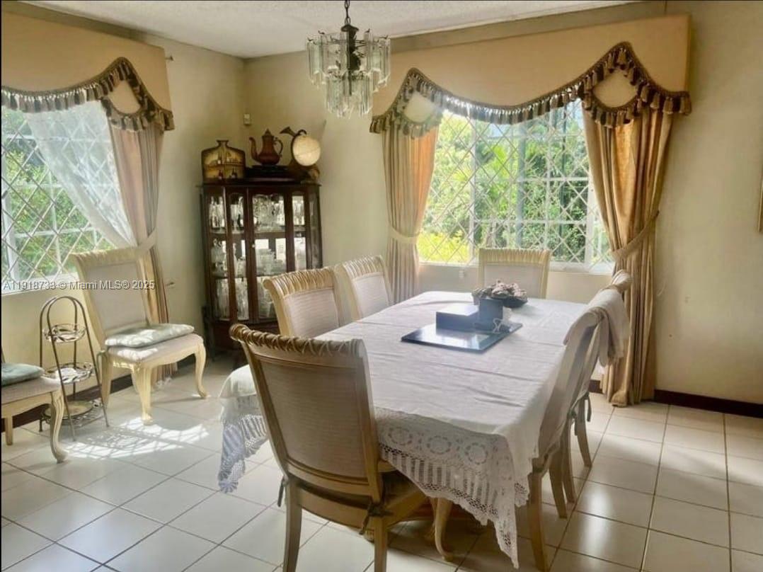 A dining room features a table with chairs, a crystal chandelier, and large curtained windows — 00 WEST PALM GARDENS, BRUMALIA, MANDEVILLE,JAMAICA, NA, NA