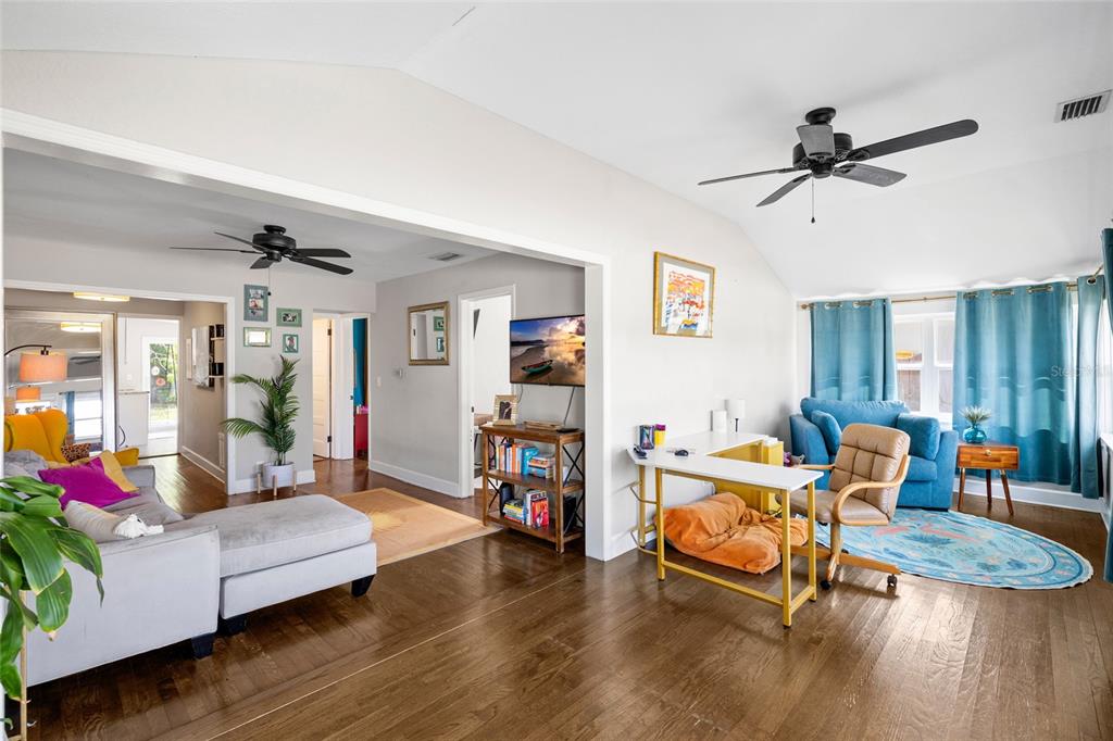 A living room with hardwood floors, a gray sectional, a desk, and blue curtains — 466 36TH AVENUE N, ST PETERSBURG, FL