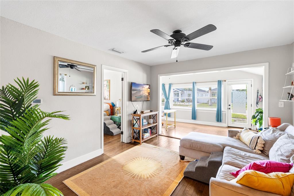 A living room with a sectional sofa, area rug, ceiling fan, and an adjacent sunroom — 466 36TH AVENUE N, ST PETERSBURG, FL