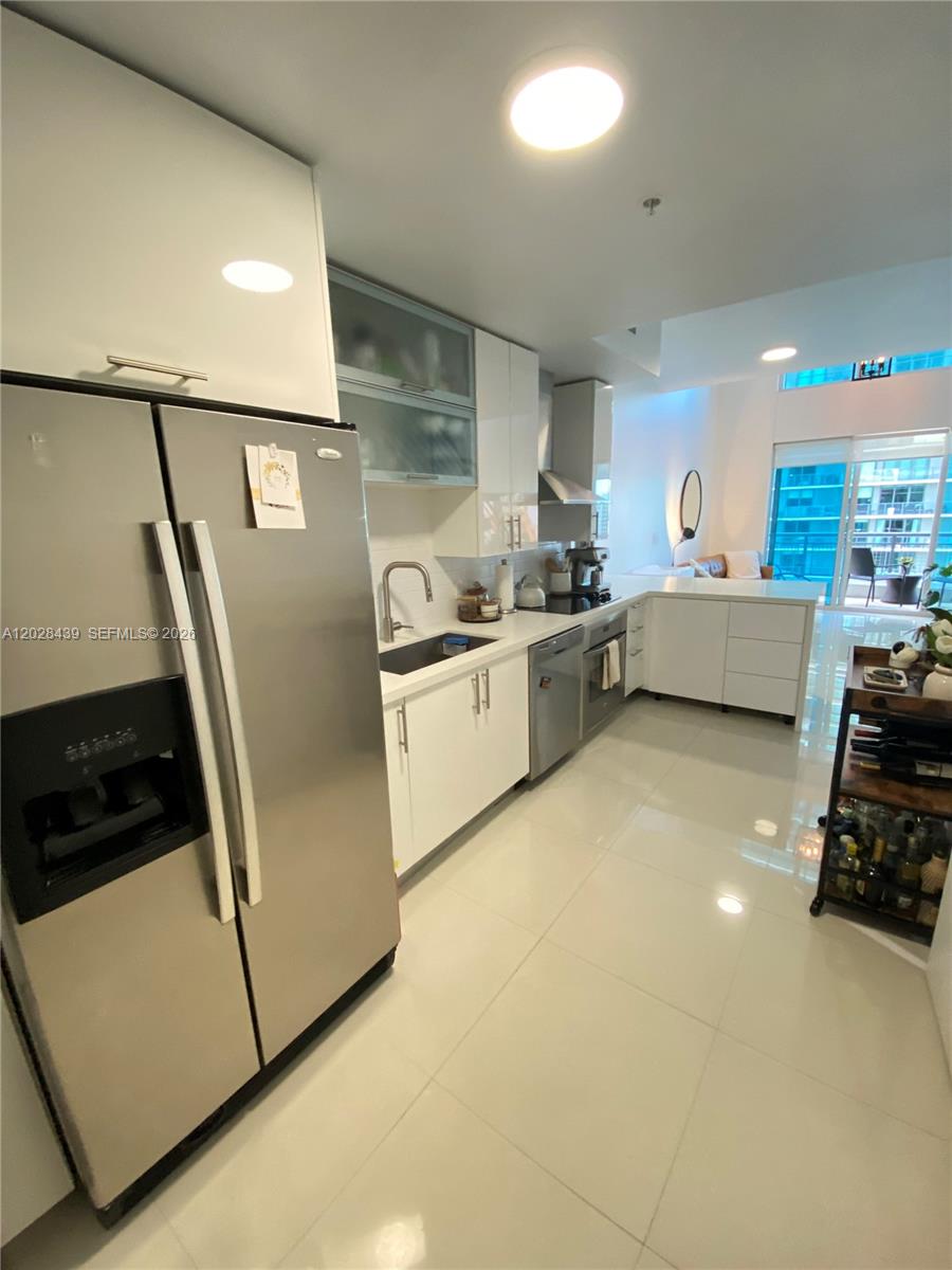 A modern kitchen features white cabinetry, stainless steel appliances, and glossy tile flooring — 60 SW 13th St # 2212, Miami FL 33130, MIAMI, FL