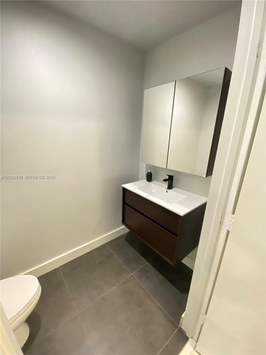 A small bathroom features a floating vanity, a medicine cabinet, and dark floor tiles — 60 SW 13th St # 2212, Miami FL 33130, MIAMI, FL