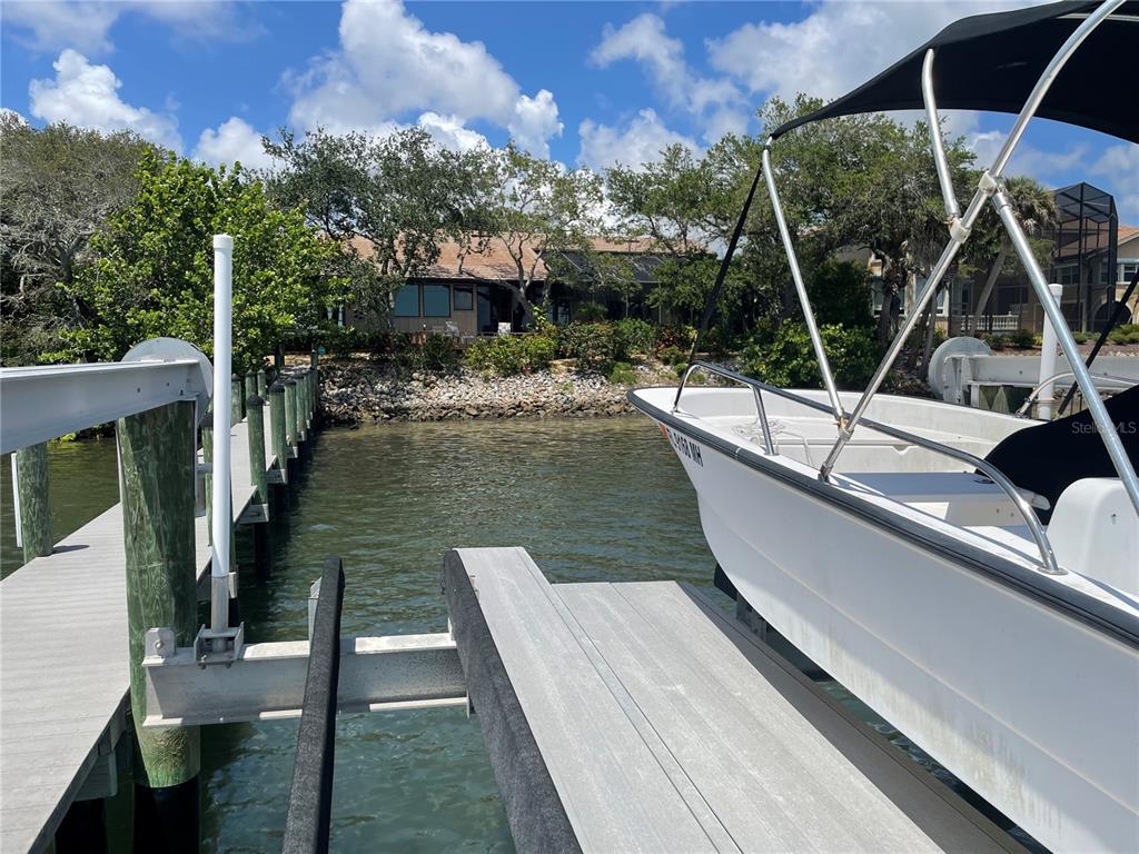 A boat is docked at a wooden pier in front of a waterfront house — 421 WATERSIDE LANE, NOKOMIS, FL