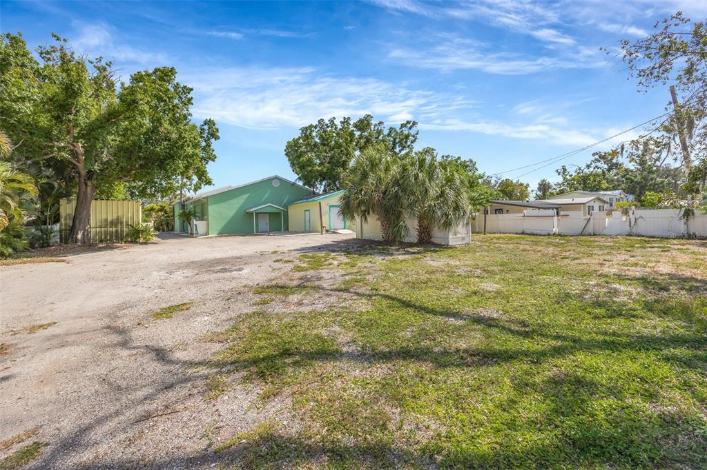 A green building sits on a large, unpaved lot with trees and a white fence — 826 W SHELL POINT STREET, RUSKIN, FL