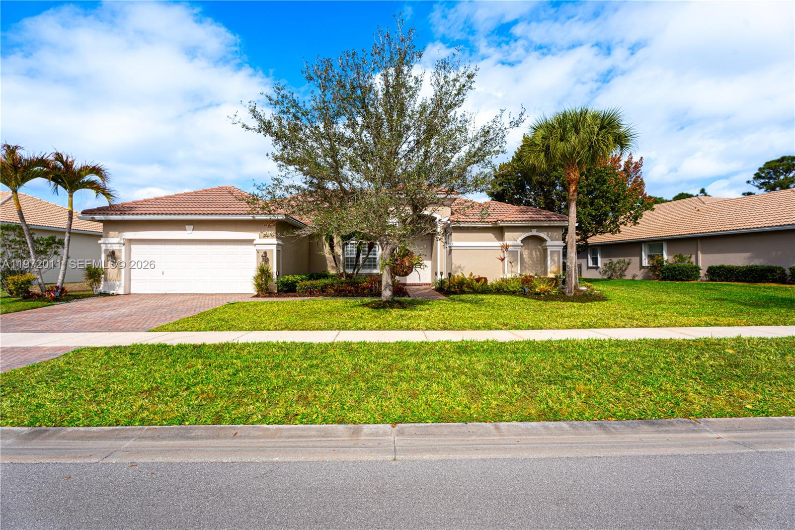 A single-story suburban house with a tile roof, garage, and palm trees in the front yard — 6918 SE Sleepy Hollow Ln, Stuart FL 34997, STUART, FL