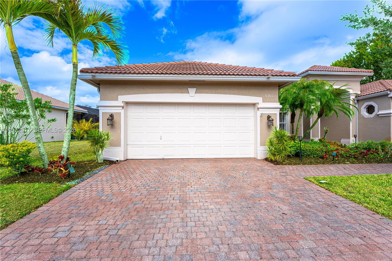 A single-story house with a tan stucco exterior, a tile roof, and a paved driveway — 6918 SE Sleepy Hollow Ln, Stuart FL 34997, STUART, FL