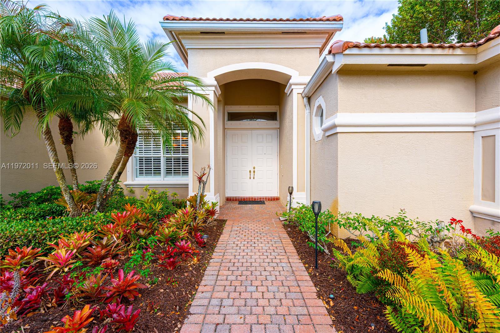 A beige house with a two-car garage and a brick paver driveway — 6918 SE Sleepy Hollow Ln, Stuart FL 34997, STUART, FL