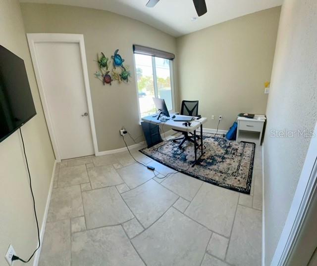 A home office features tile flooring, a desk with a computer, and a decorative wall hanging — 501 BAL HARBOR BOULEVARD, PUNTA GORDA, FL