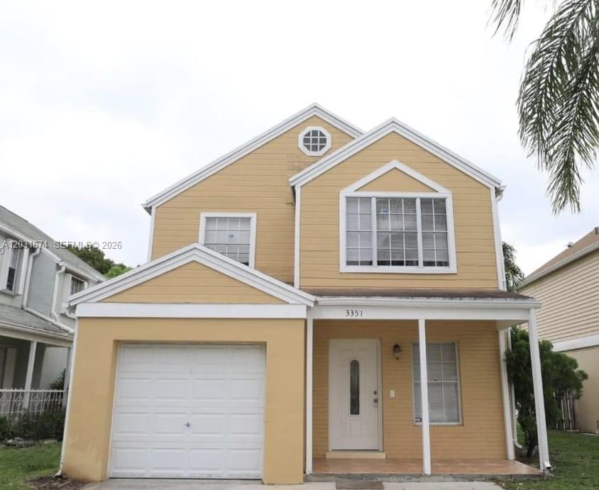 A two-story yellow house with a single-car garage and a covered front porch — MIRAMAR, FL