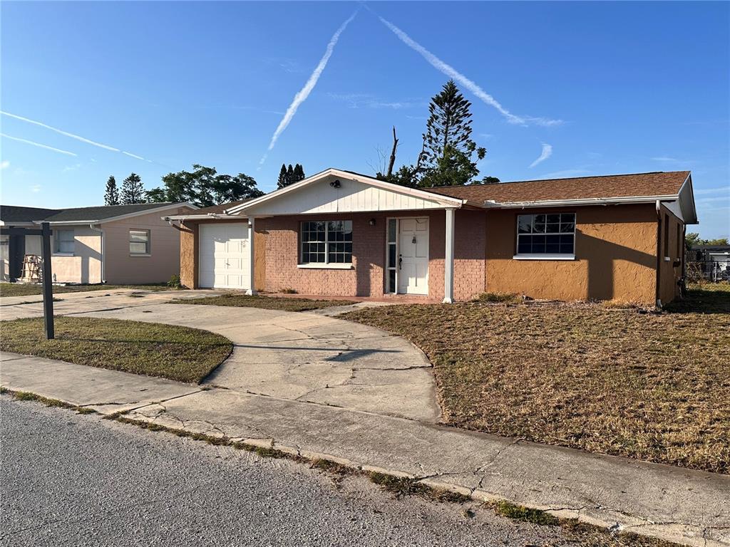 A single-story house with a brick facade, a white front door, and a concrete driveway — 3215 BRIGHT DRIVE, HOLIDAY, FL
