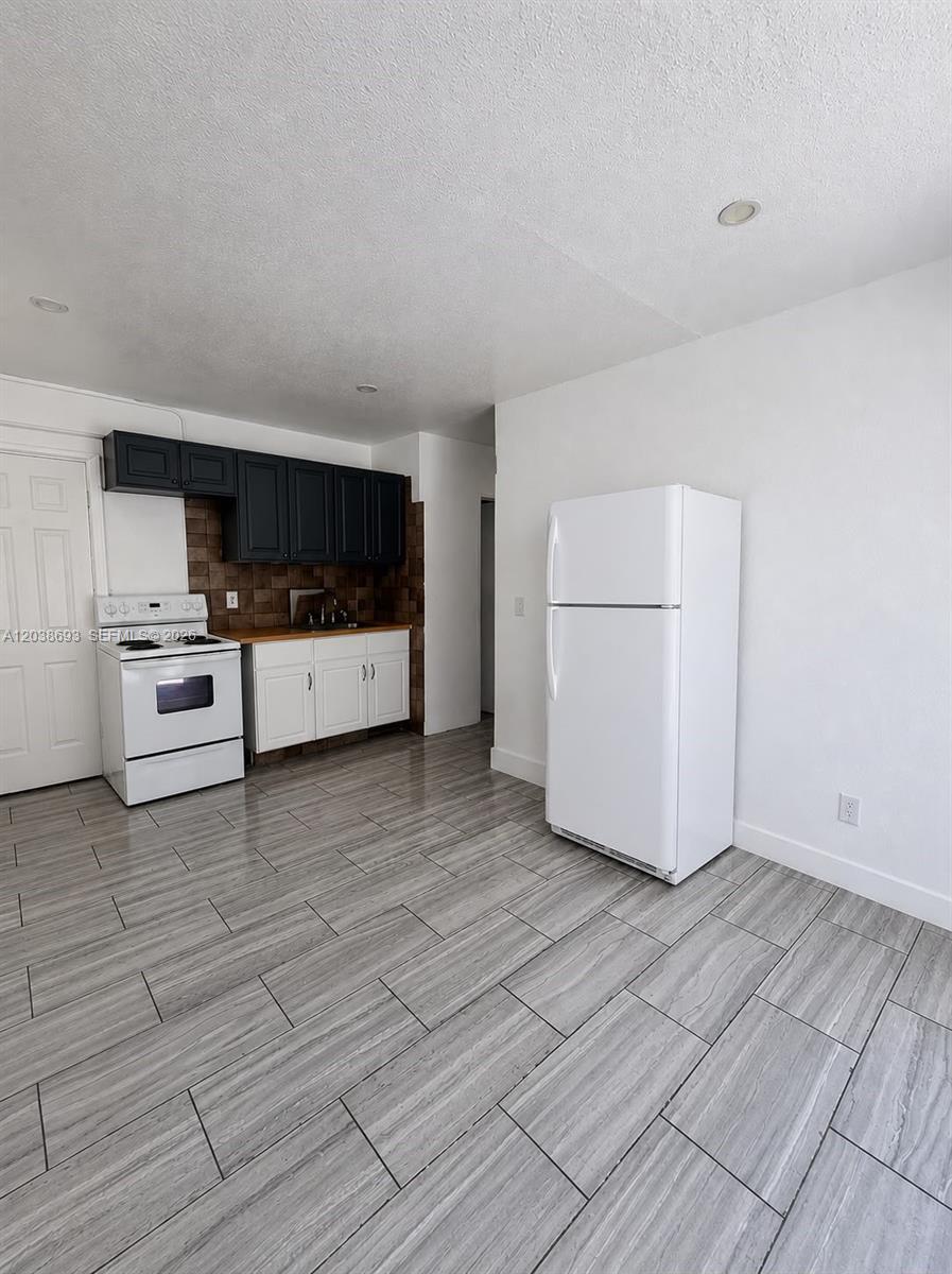 A kitchen features white lower cabinets, black upper cabinets, a white stove, and gray flooring — FLORIDA CITY, FL