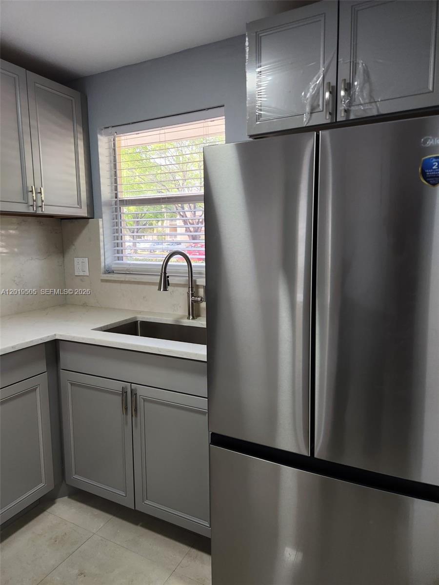 A kitchen features gray cabinets, stainless steel appliances, and a window above the sink — 2811 N Pine Island Rd # 107, Sunrise FL 33322, SUNRISE, FL