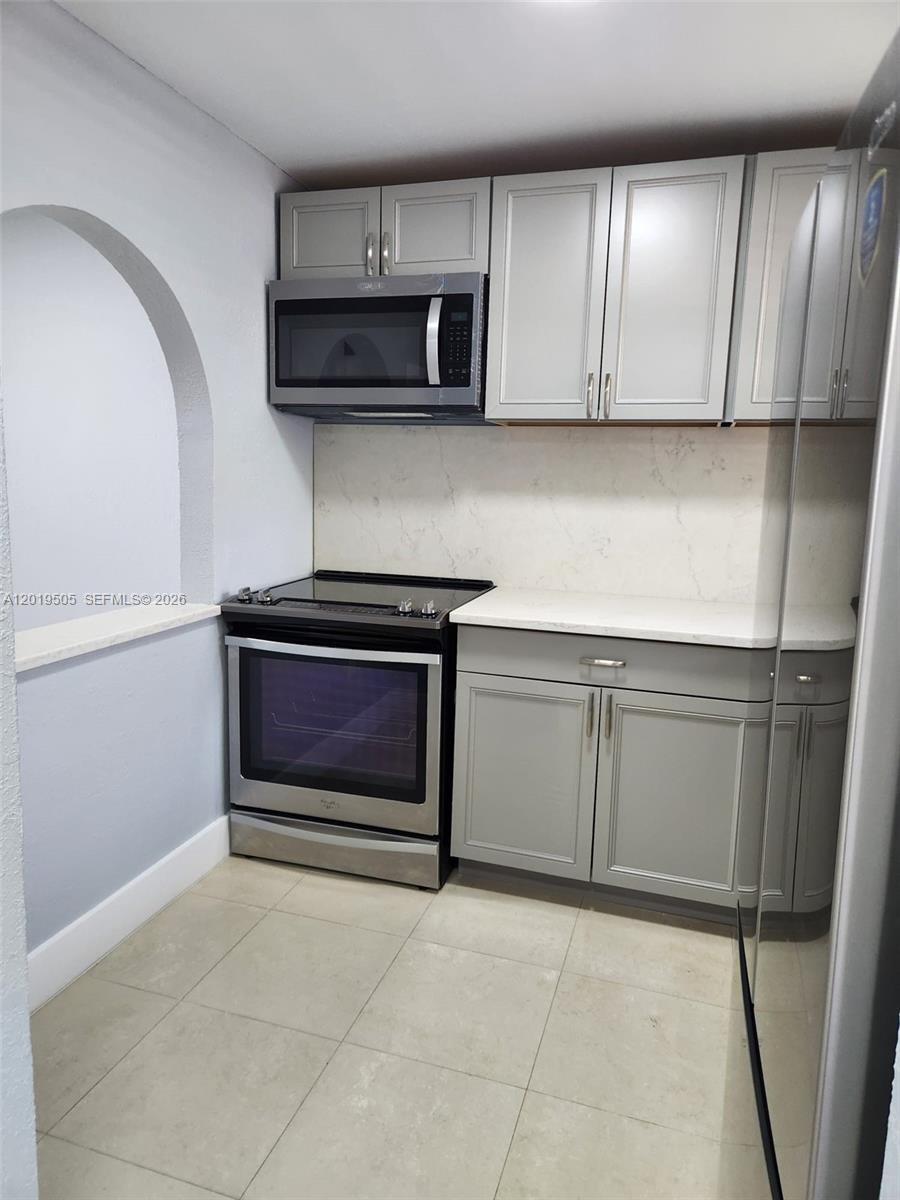 A kitchen features gray cabinets, stainless steel appliances, and light-colored countertops — 2811 N Pine Island Rd # 107, Sunrise FL 33322, SUNRISE, FL