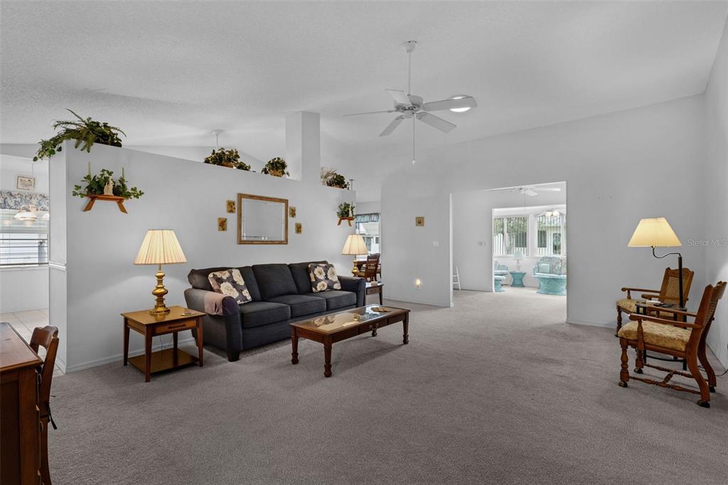 A living room features a dark sofa, a coffee table, and a partial wall divider — 6033 WADE STREET, LEESBURG, FL