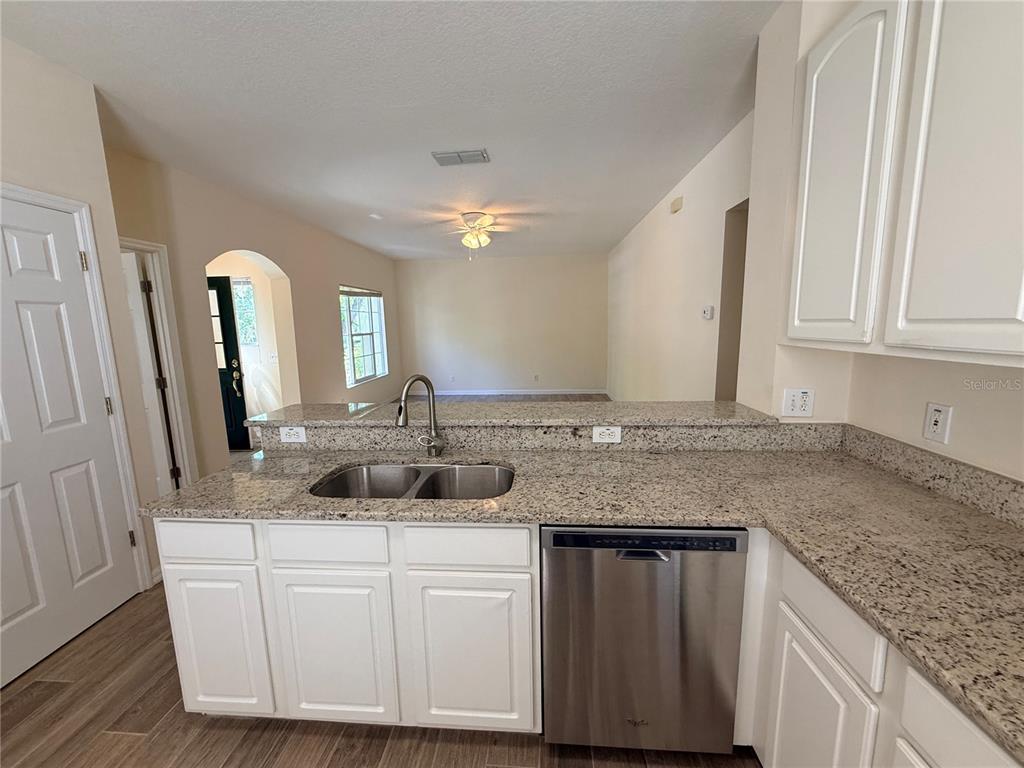 A kitchen features white cabinets, granite countertops, a stainless steel dishwasher, and a double sink — 1107 CROTON PLACE, CELEBRATION, FL