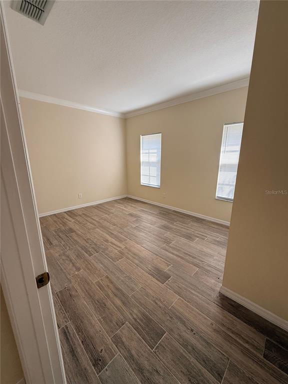 An empty room features light-colored walls, crown molding, and wood-look tile flooring — 1107 CROTON PLACE, CELEBRATION, FL