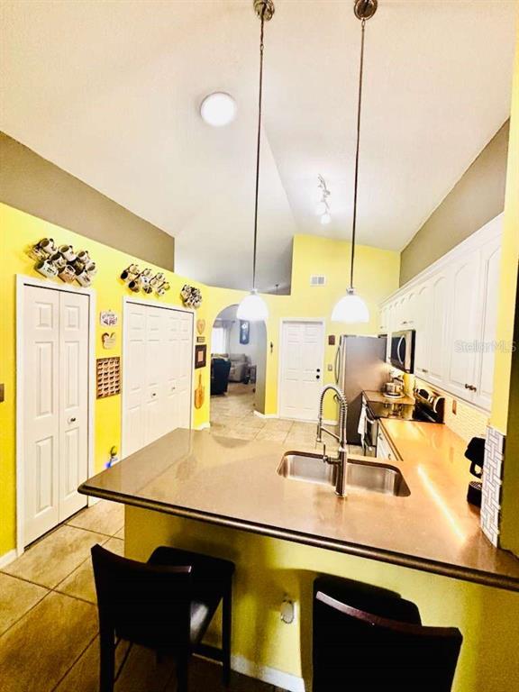 A living room and dining area with tile floors, a ceiling fan, and vaulted ceilings — 14224 RENSSELAER ROAD, ORLANDO, FL