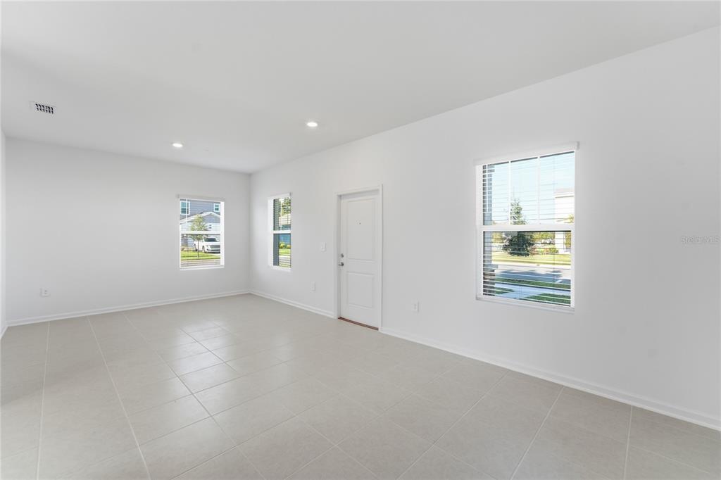 An empty room with white walls, tiled floors, a door, and three windows — 2196 RED SUN STREET, APOPKA, FL