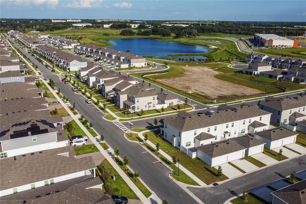 An aerial view shows a suburban neighborhood with rows of townhomes and a central pond — 2196 RED SUN STREET, APOPKA, FL