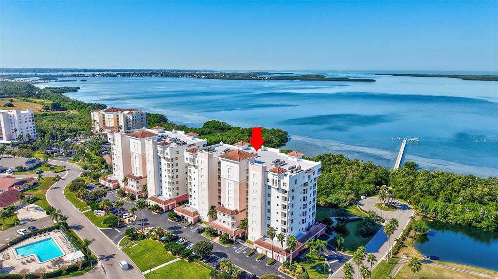 An aerial view shows a multi-story residential building complex situated along a coastal waterfront — 2925 TERRA CEIA BAY BOULEVARD UNIT 2703, PALMETTO, FL