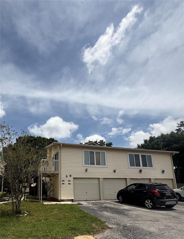 A two-story residential building with beige siding, three garage doors, and a black car parked — 1101 SPRING MEADOW DRIVE UNIT 1101, KISSIMMEE, FL