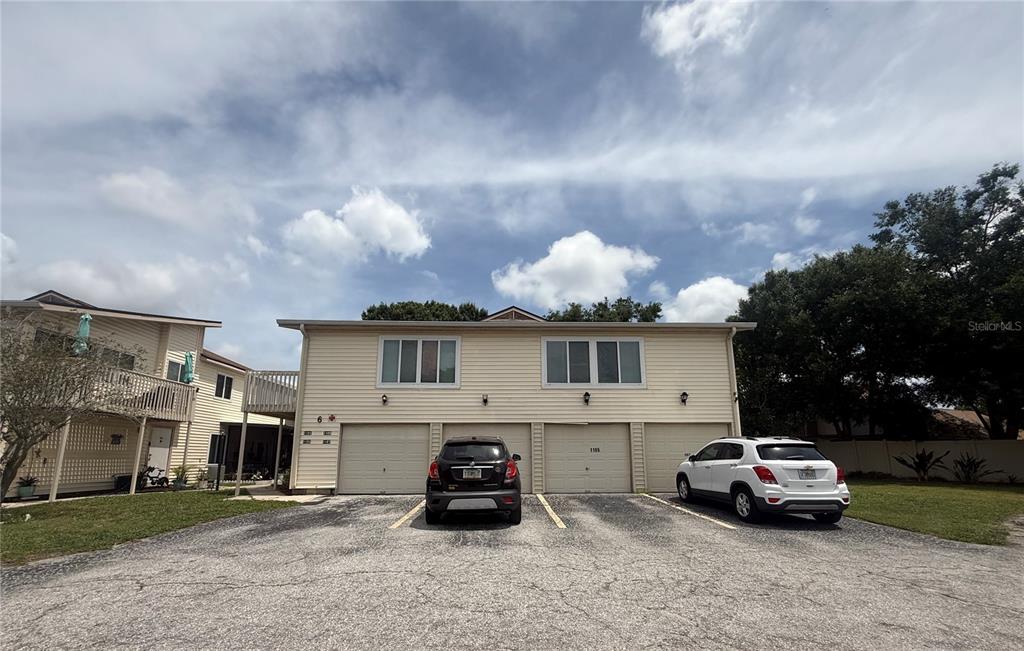 A two-story residential building with three garage doors and two parked cars in front — 1101 SPRING MEADOW DRIVE UNIT 1101, KISSIMMEE, FL