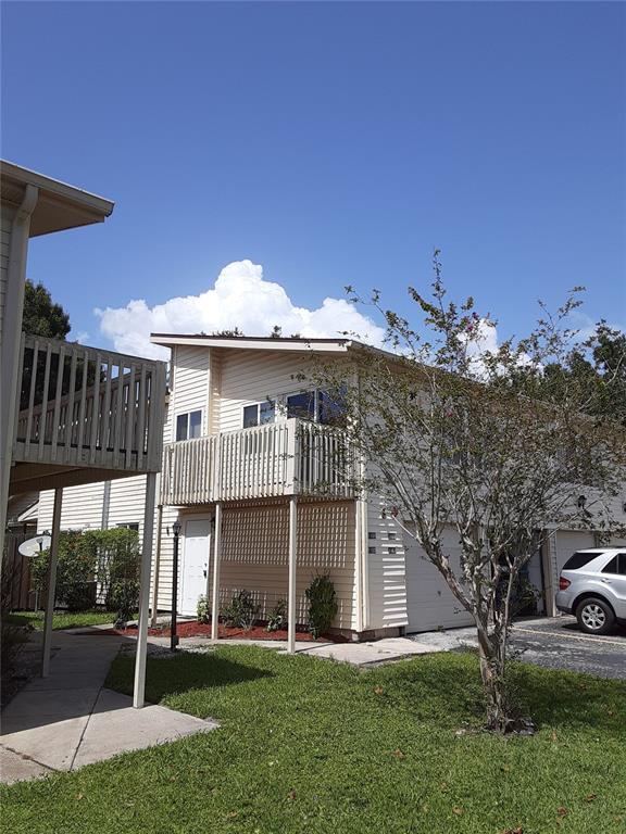 A two-story tan townhouse with a balcony, a white front door, and a garage — 1101 SPRING MEADOW DRIVE UNIT 1101, KISSIMMEE, FL