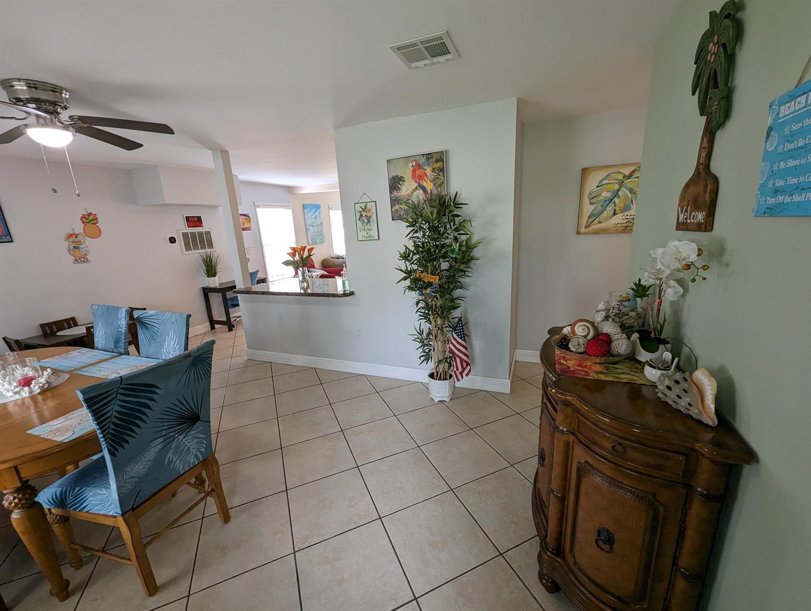A dining area with a wooden table and blue chairs opens to a kitchen counter — 2394 Zeder Avenue, Delray Beach FL 33444, DELRAY BEACH, FL