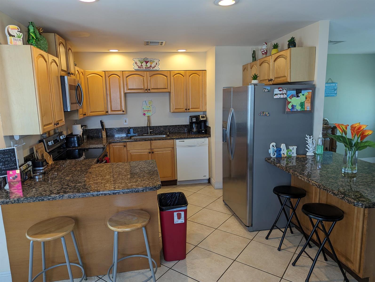 A kitchen with light wood cabinets, granite countertops, stainless steel appliances, and a breakfast bar — 2394 Zeder Avenue, Delray Beach FL 33444, DELRAY BEACH, FL