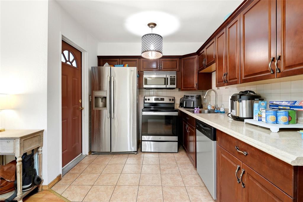 A kitchen features dark wood cabinets, stainless steel appliances, and light-colored tile flooring — 7301 8TH STREET N, ST PETERSBURG, FL