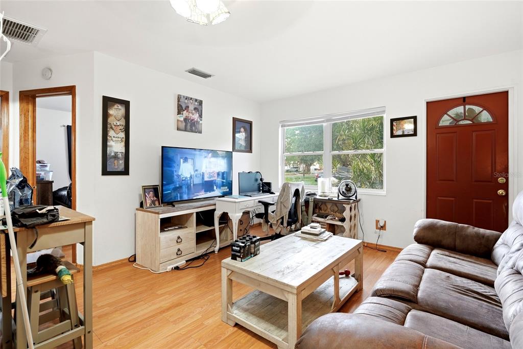 A living room features a brown sofa, a coffee table, a television, and a desk — 7301 8TH STREET N, ST PETERSBURG, FL