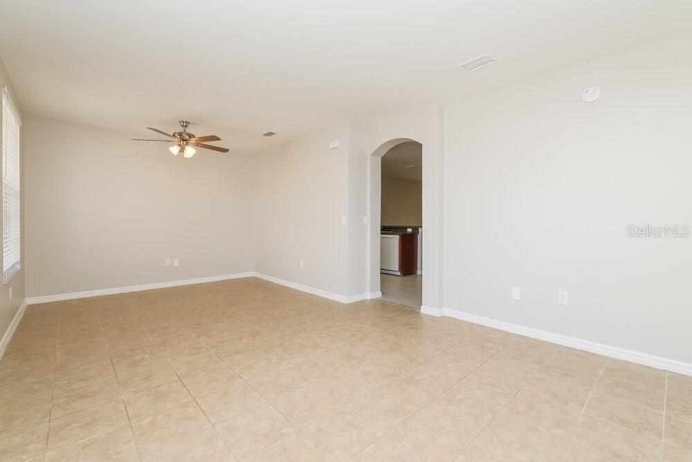 An empty room with beige tile flooring, light walls, and a ceiling fan — 5048 CACTUS NEEDLE LANE, WESLEY CHAPEL, FL