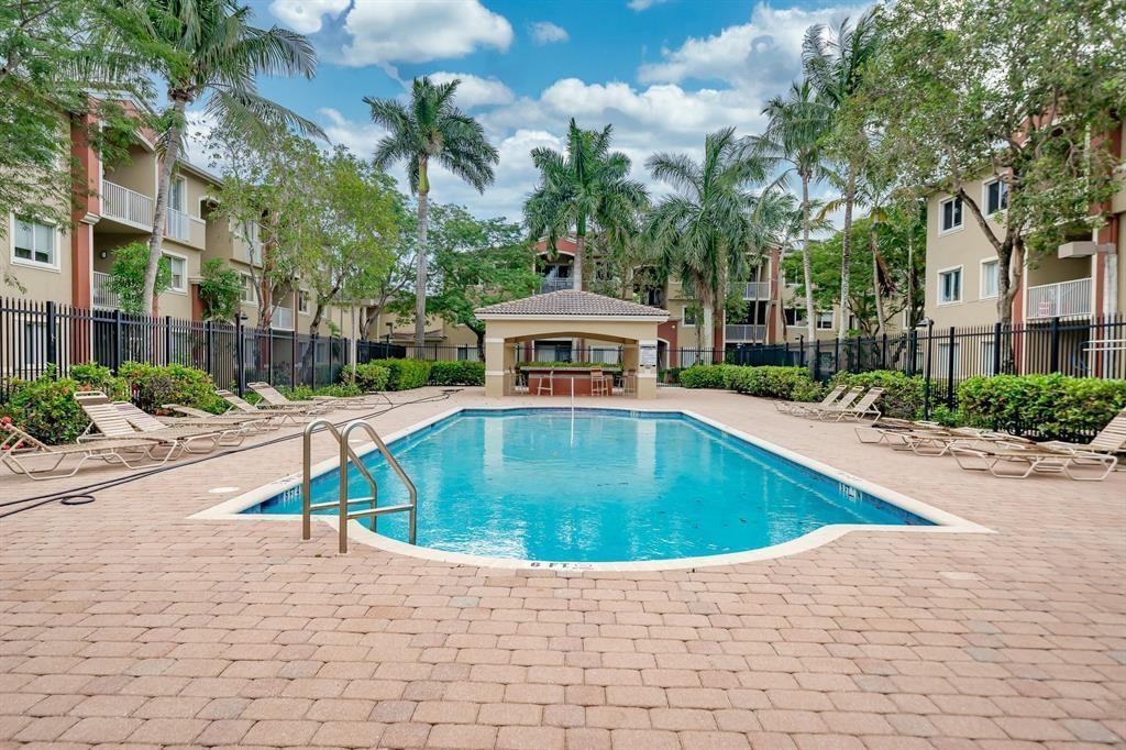 A swimming pool with a central cabana is surrounded by apartment buildings and palm trees — 7085 Nova Drive # 226, Davie FL 33317, DAVIE, FL